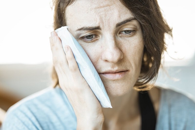 patient model with jaw pain holding a tower over their jaw