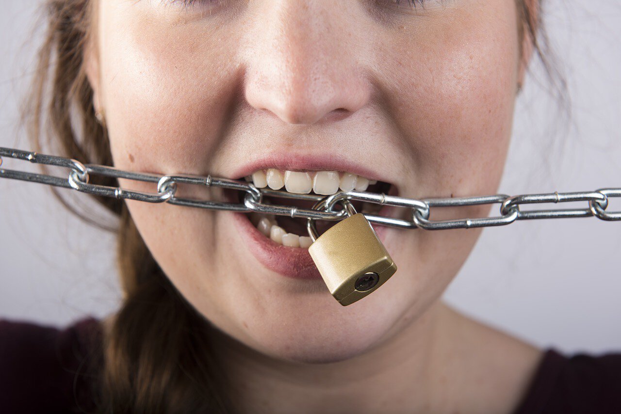 TMJ treatment patient model biting a lock attached to a chain