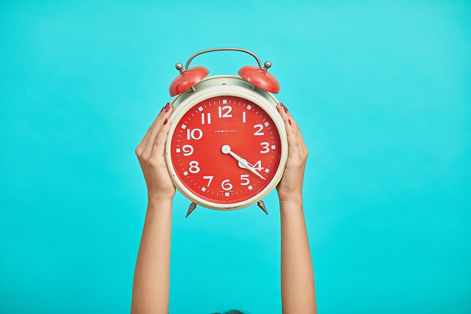 hands holding up a retro alarm clock